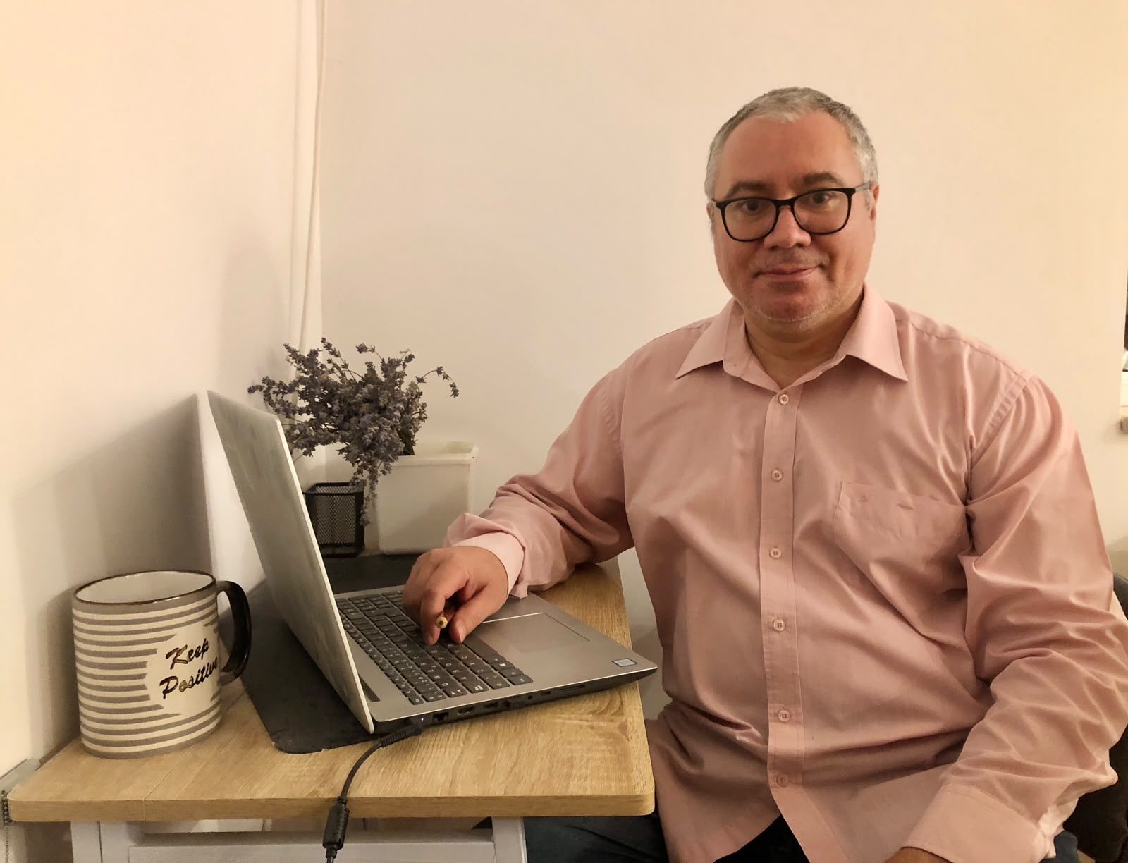 Virgil Ionut Deaconu, founder and lead teacher, smiling at his desk with a laptop and coffee